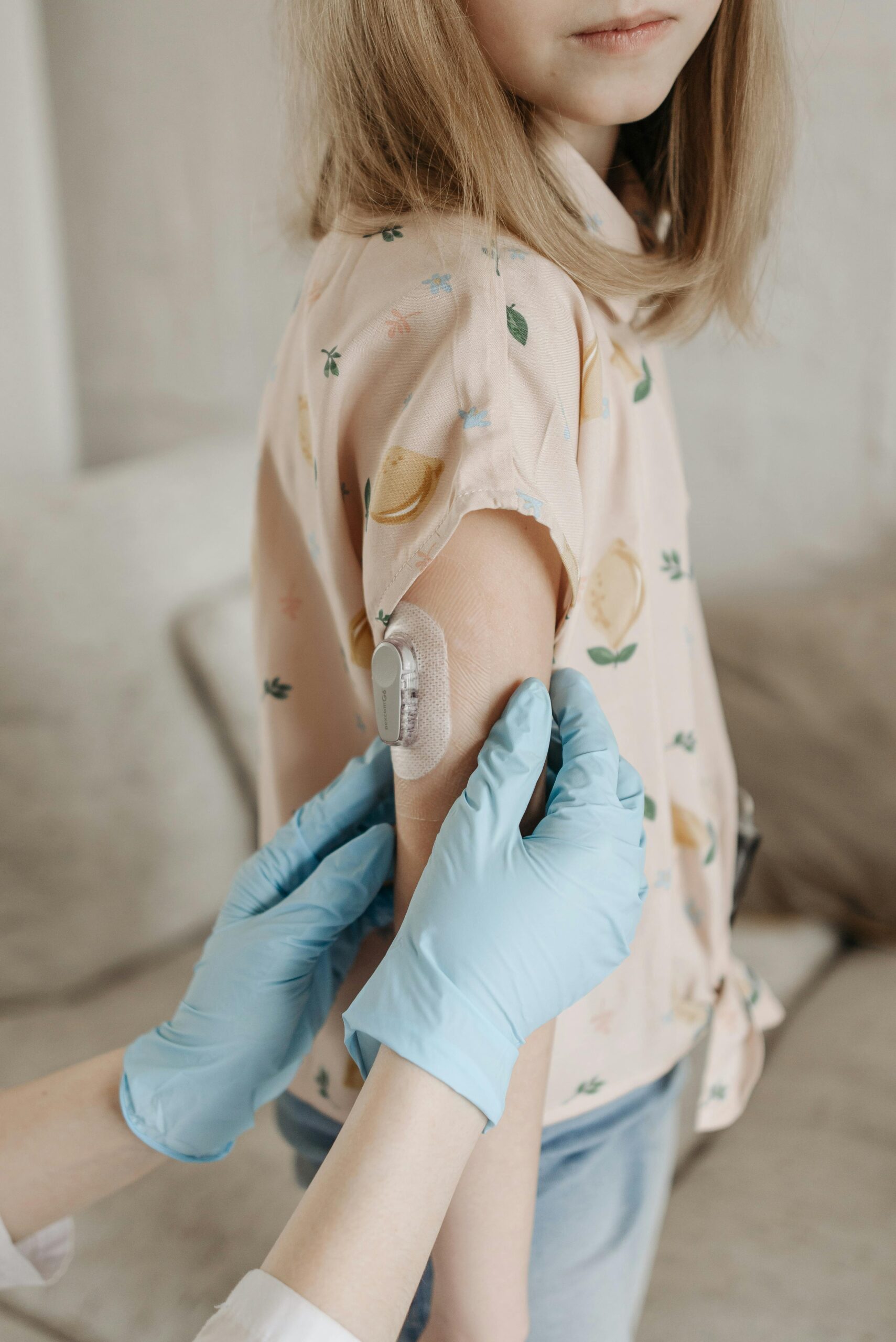 Young girl wearing a continuous glucose monitor (CGM) on her upper arm, representing diabetes therapy services.