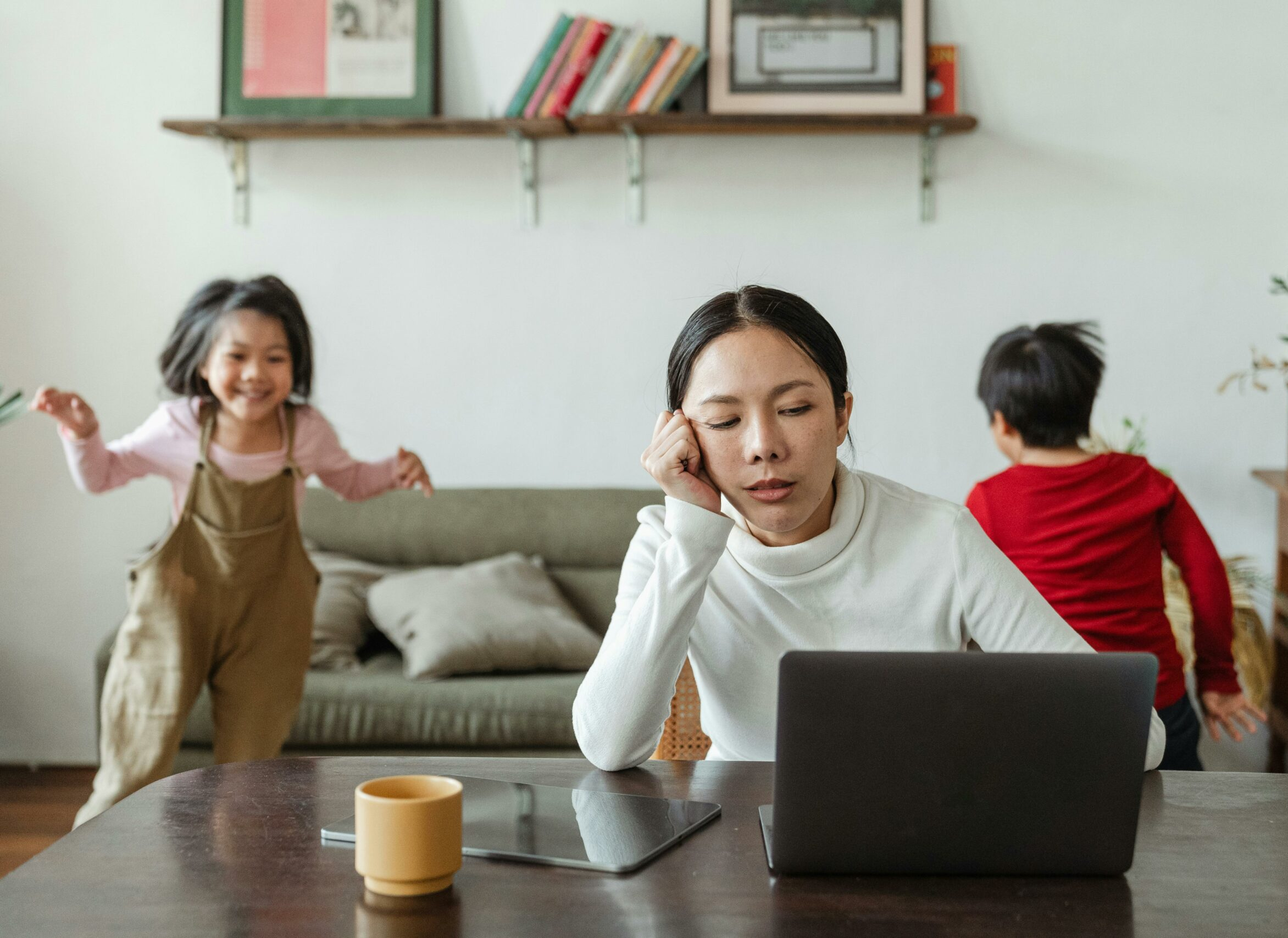 Parent feeling overwhelmed while working from home as young children play in the background