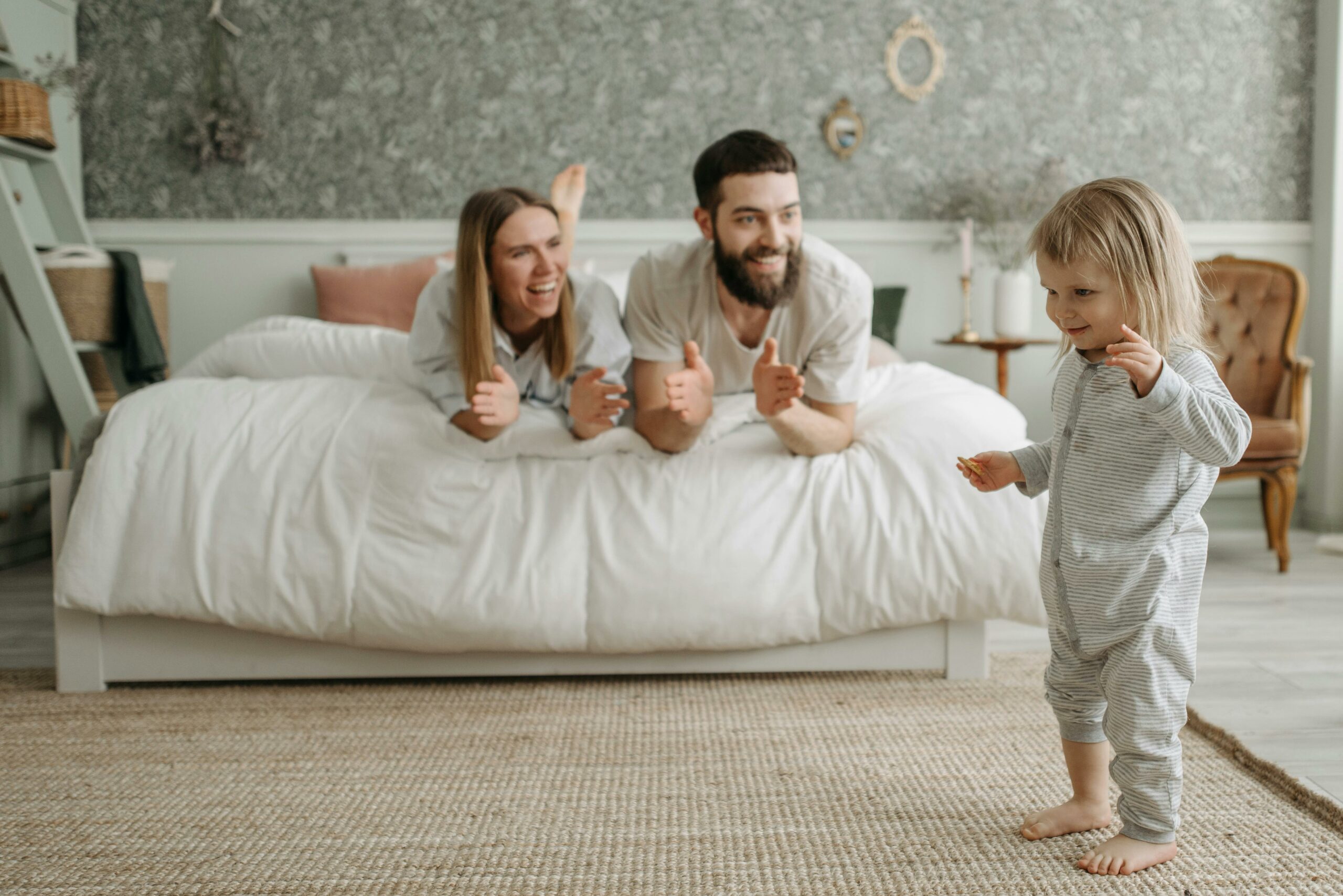 Parents encouraging their toddler as they take early steps, reflecting connection and supportive parenting
